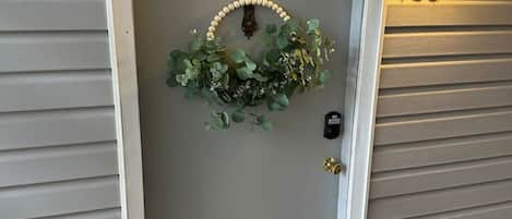 A door with a wreath, a number '106' on the wall, and a colorful doormat.
