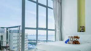 A modern hotel room with a large window, a bed with two plush toys, and a chair by the window. - Penang Straits Garden Georgetown (George Town)