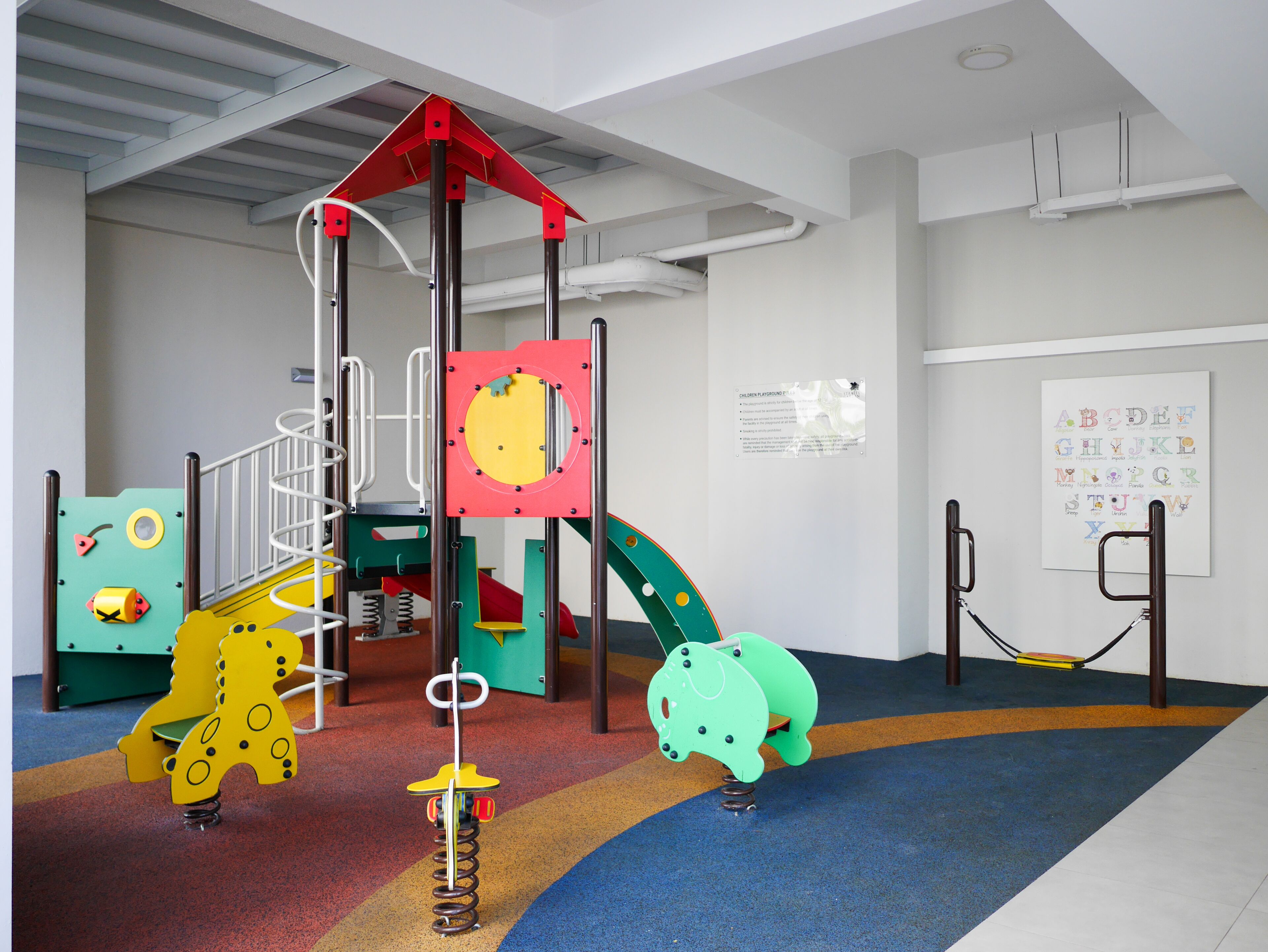 Een kinderspeelplaats met een klimstructuur, een glijbaan en een zachte speelbodem.
