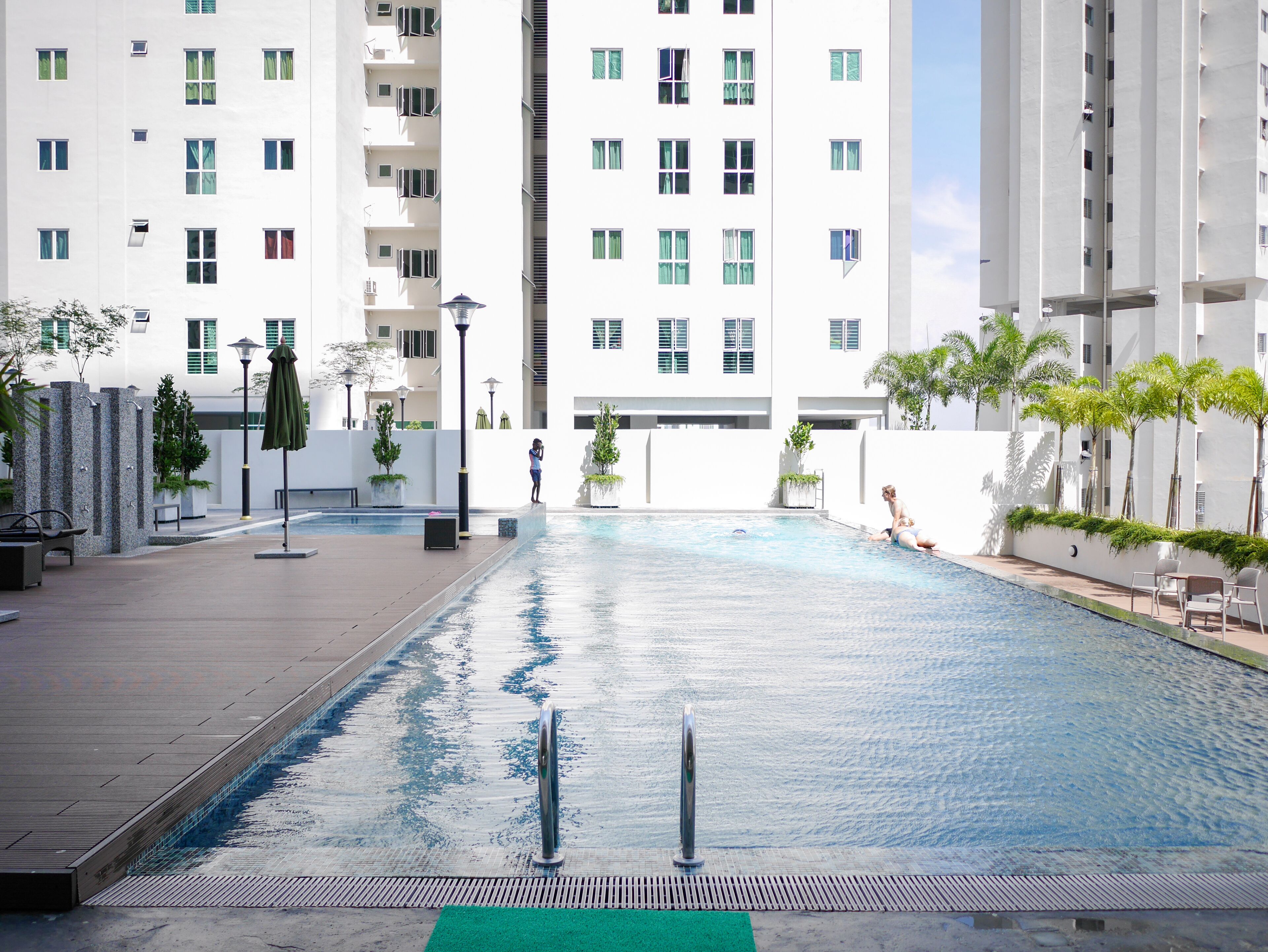 A swimming pool with a clear view of the surrounding buildings, including a high-rise apartment building.