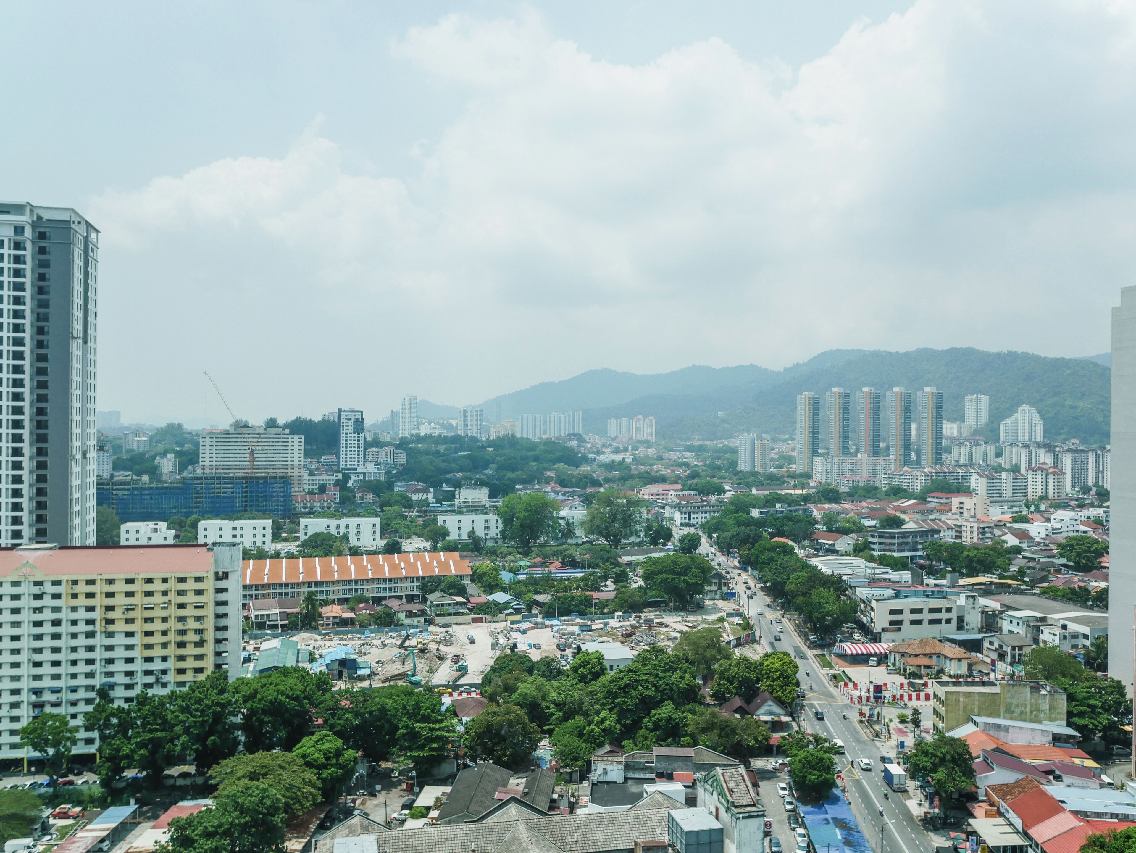 Un paisaje urbano que muestra edificios residenciales y comerciales, una avenida central y zonas verdes circundantes.