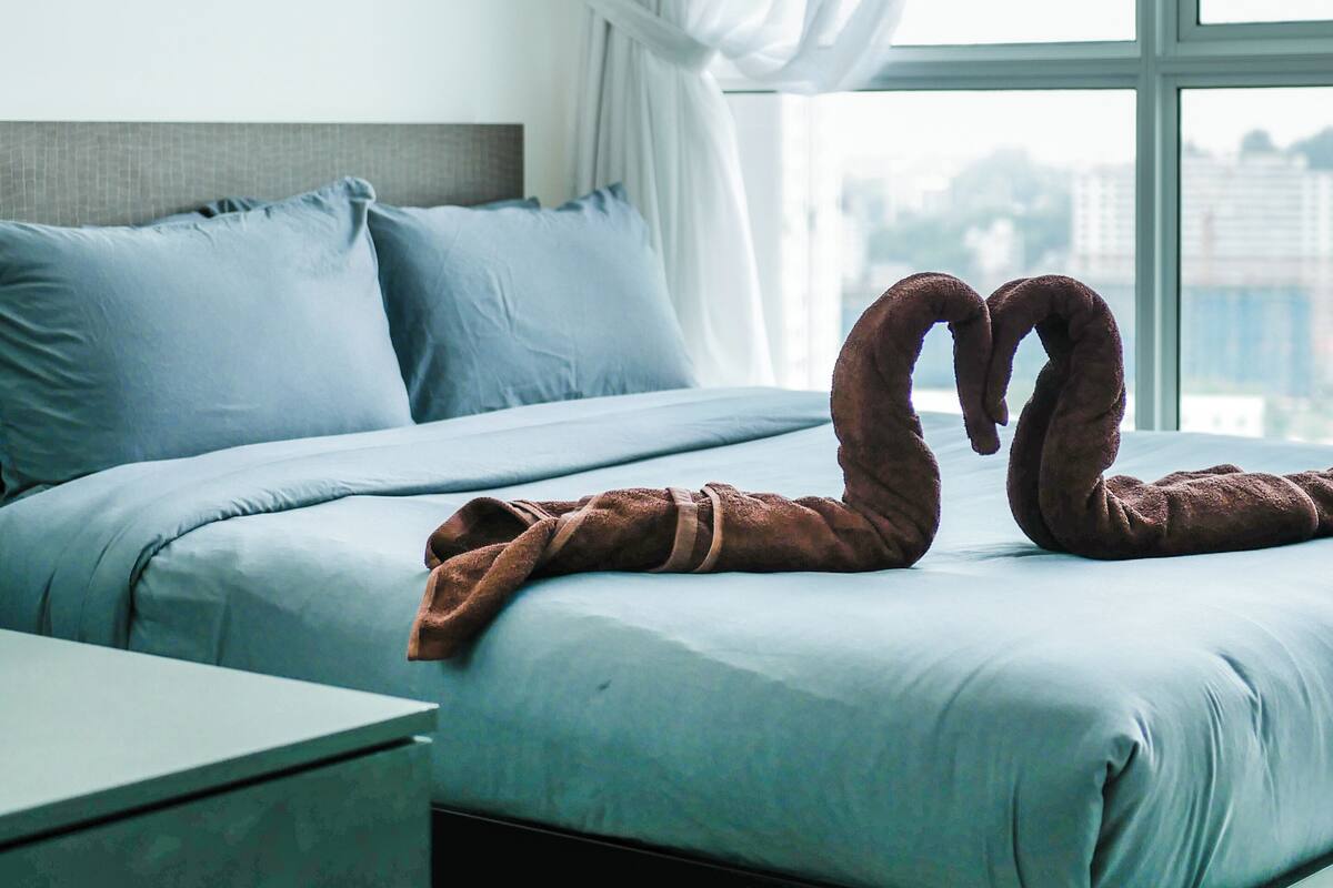 A bedroom with a bed, pillows, a nightstand, and a window with curtains.