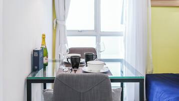 Un comedor moderno con una mesa de vidrio, sillas tapizadas de gris y una lámpara colgante de diseño geométrico.