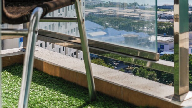 A modern chair by a large window overlooking a cityscape. - Penang Straits Garden Georgetown (George Town)