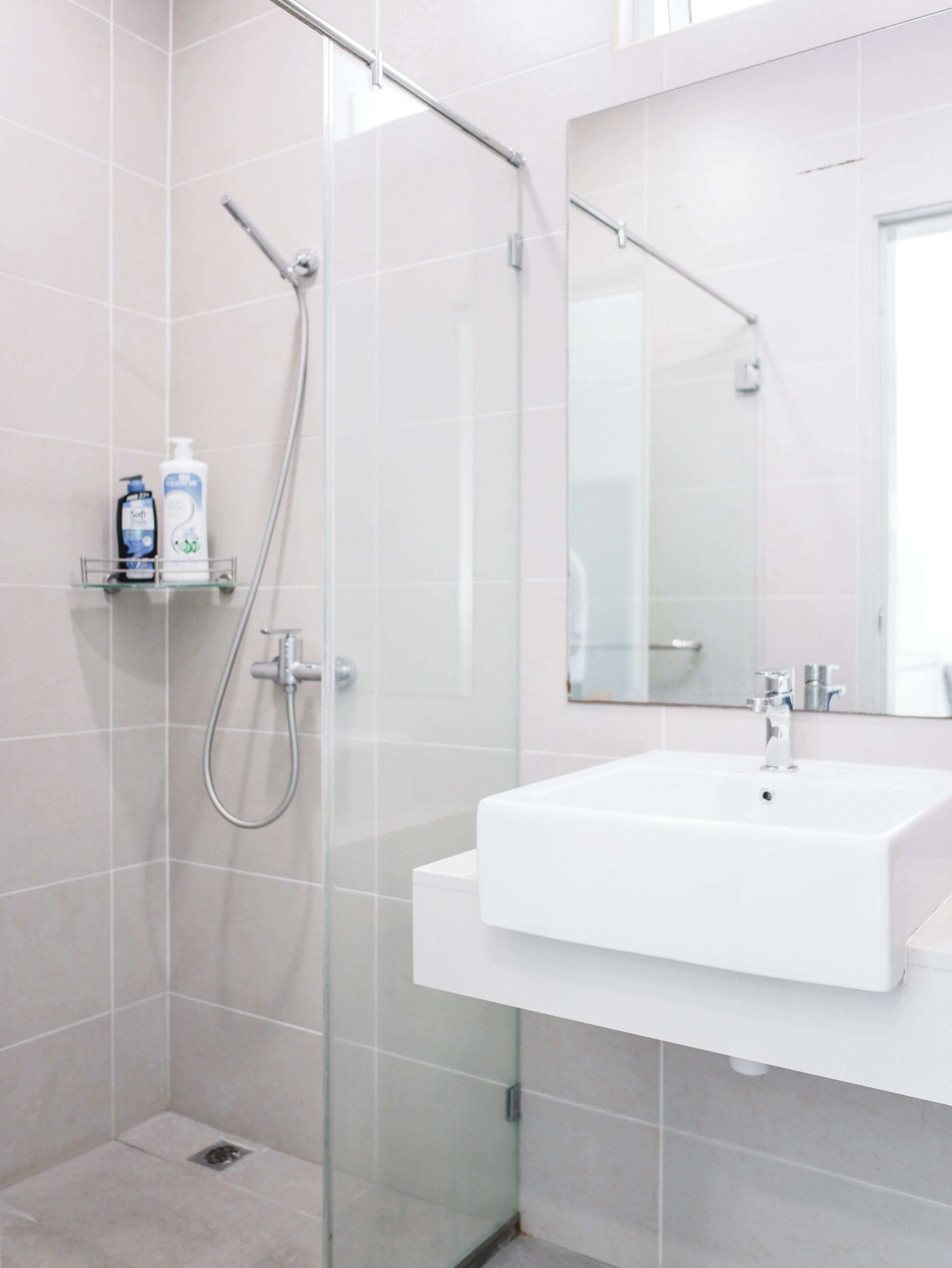 A modern bathroom with a glass shower enclosure, a white sink, and a mirror above it.