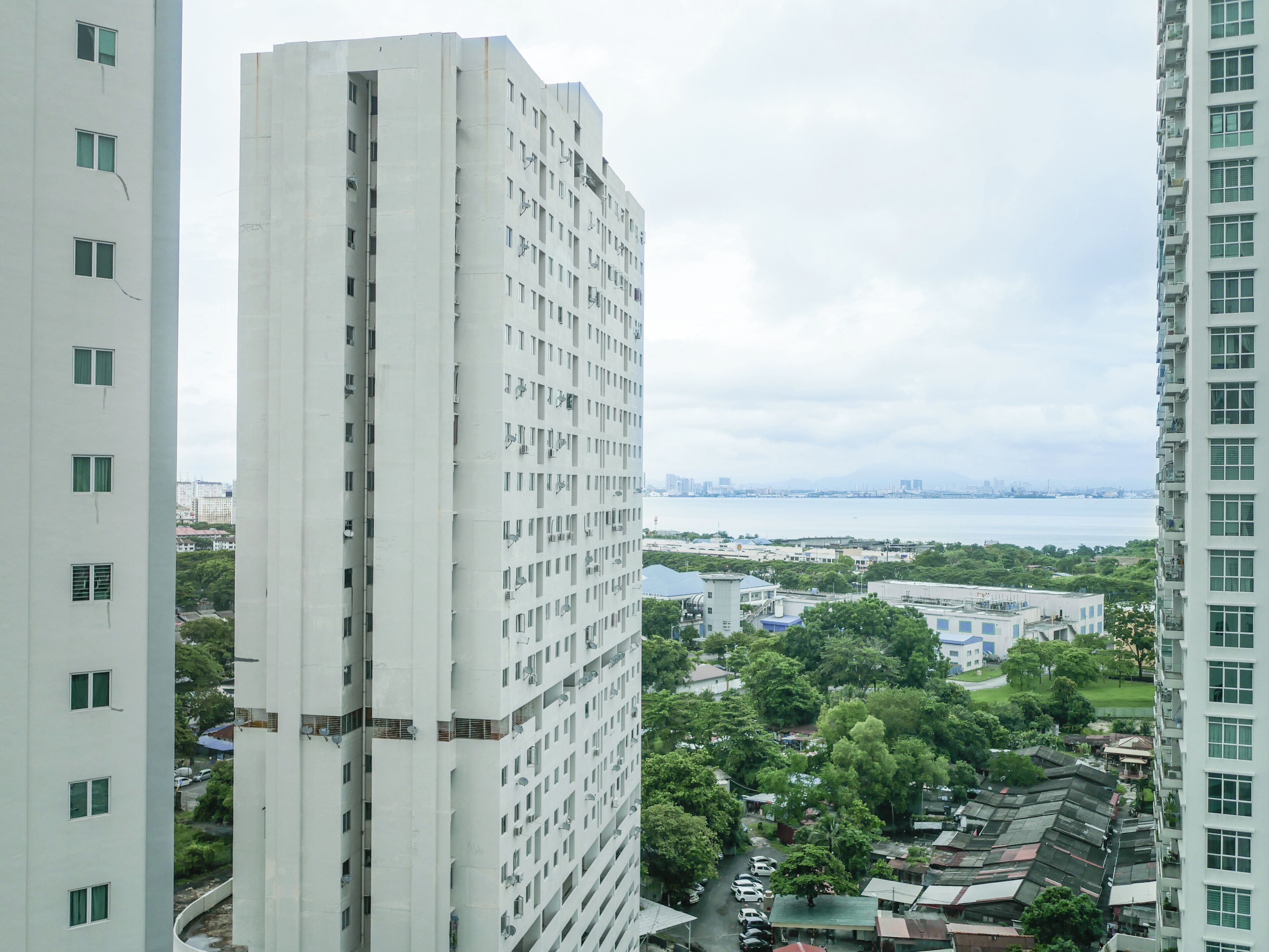Un immeuble de grande hauteur, doté de nombreux étages et de balcons, entouré de verdure et d’autres bâtiments.