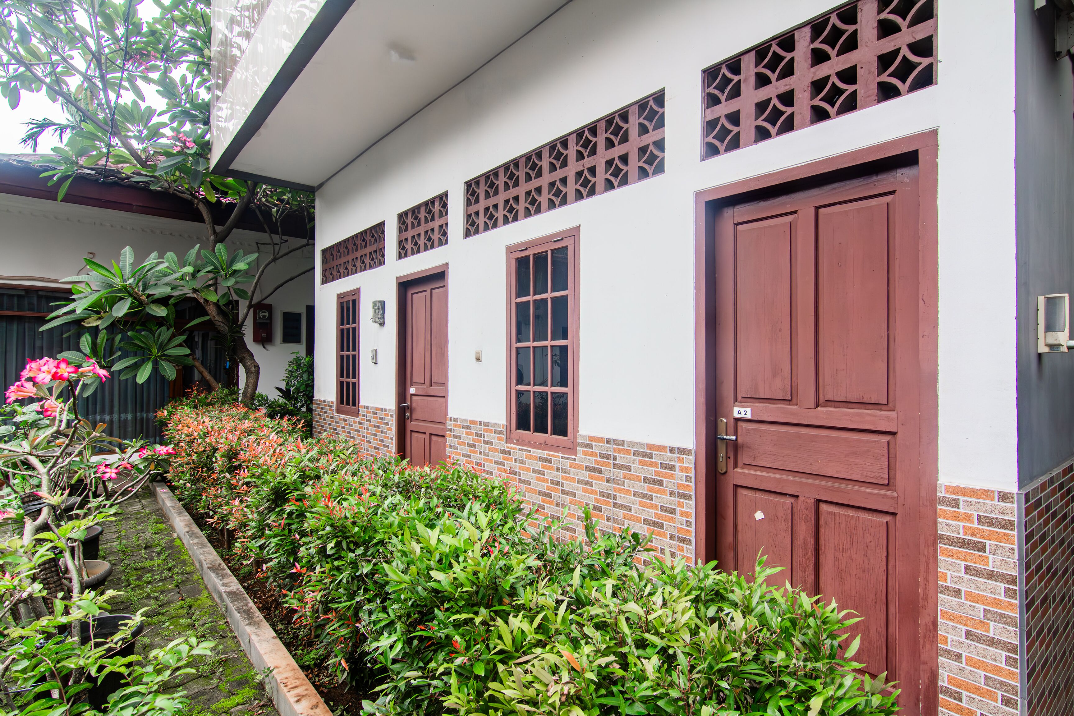 A building with two large wooden doors, a small window, and a brick base.