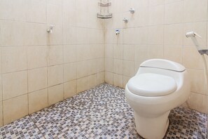 Ein Badezimmer mit Toilette, Dusche und Fliesenboden.