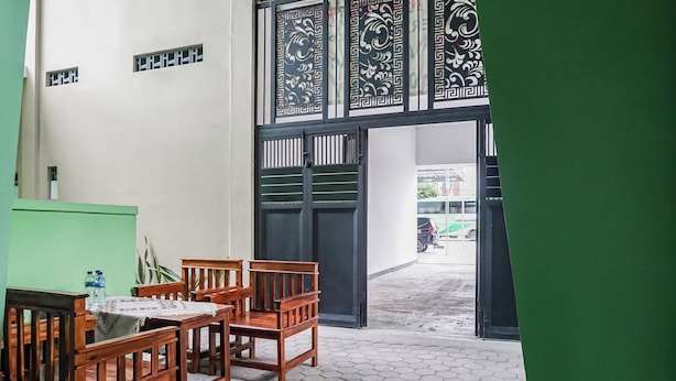 A room with a wooden table and chairs, a green wall, and a patterned door. - Hotel O Guest House Riharti Syariah (Bandar Lampung)
