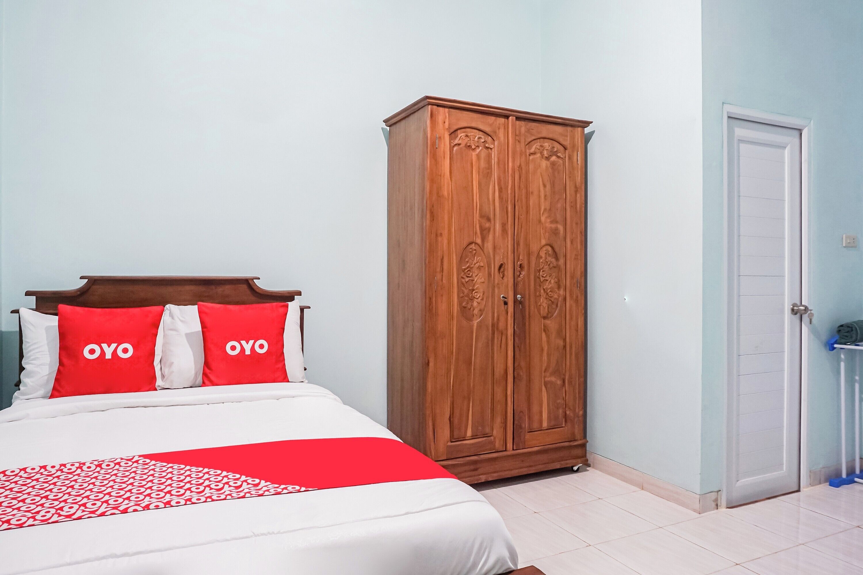 Quarto de hotel com uma cama, um guarda-roupa e uma porta.