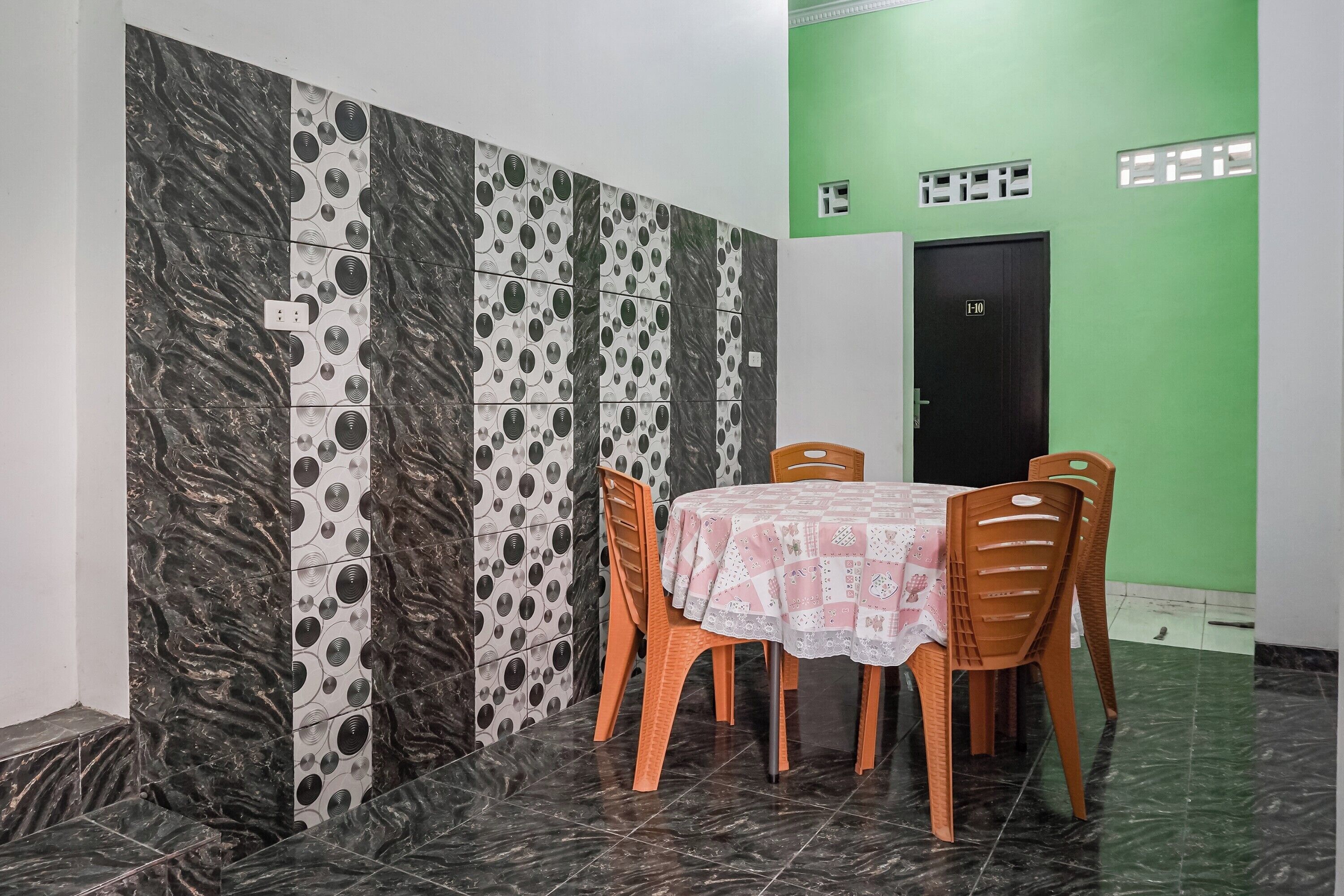 A dining area with a table and chairs, a green wall, and a door marked "I-10".