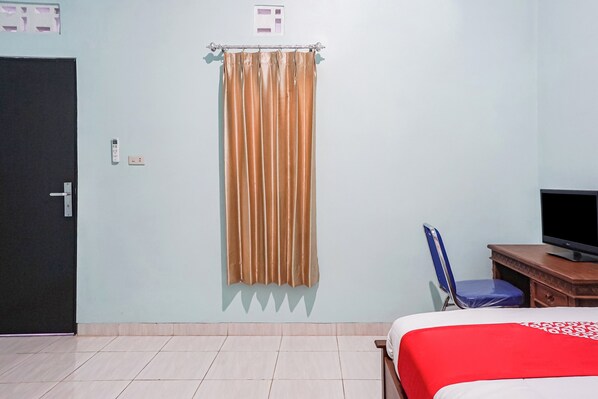 A hotel room with a bed, a television, a desk, and a chair. - Hotel O Guest House Riharti Syariah (Bandar Lampung)