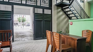 A room with a wooden desk, two chairs, a laptop, and a green wall. - Hotel O Guest House Riharti Syariah (Bandar Lampung)