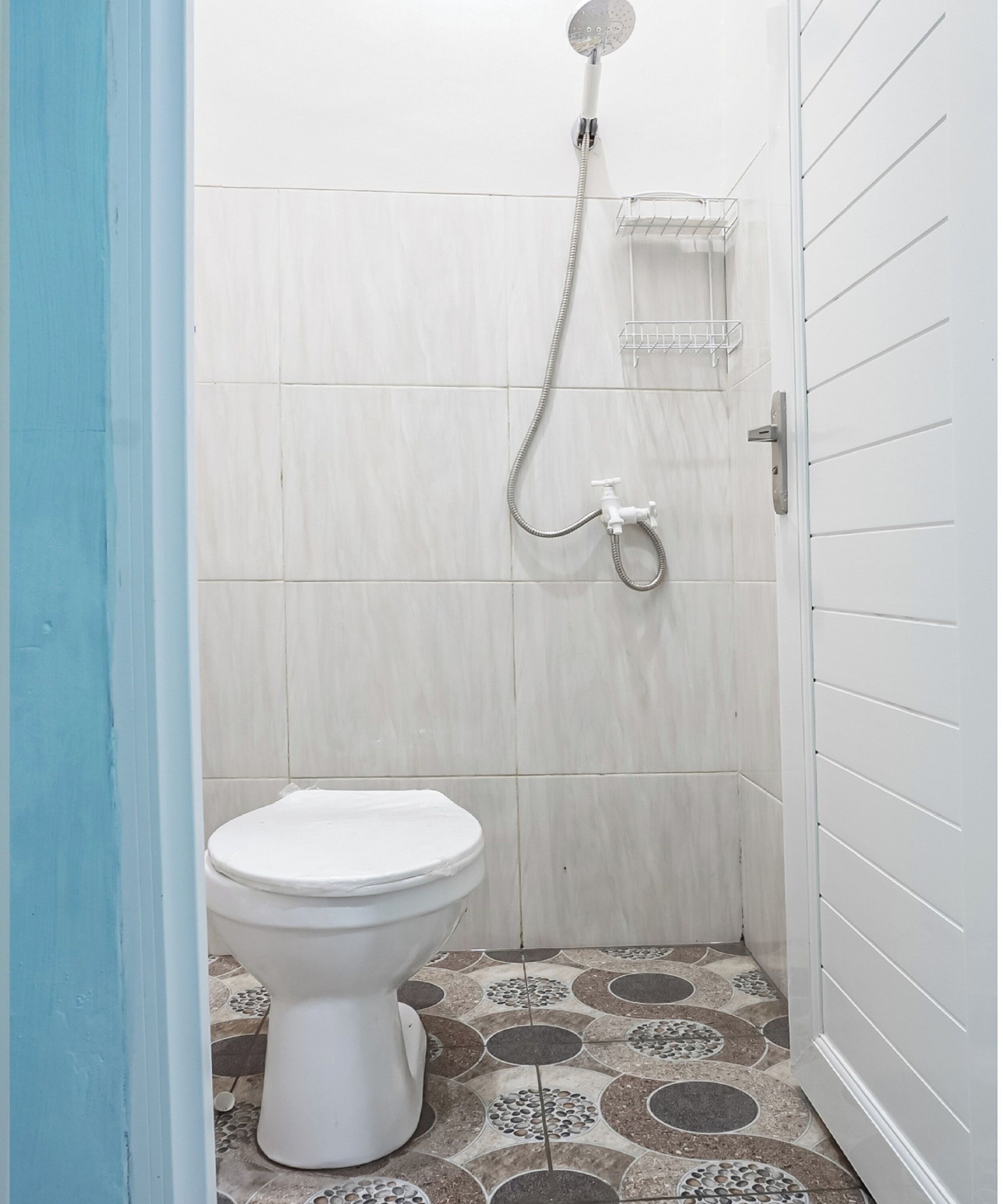 Een kleine, smalle badkamer met toilet, douche en betegelde vloer.