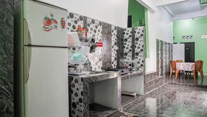 A kitchen with a refrigerator, a sink, and a dining area with chairs and a table. - Hotel O Guest House Riharti Syariah (Bandar Lampung)