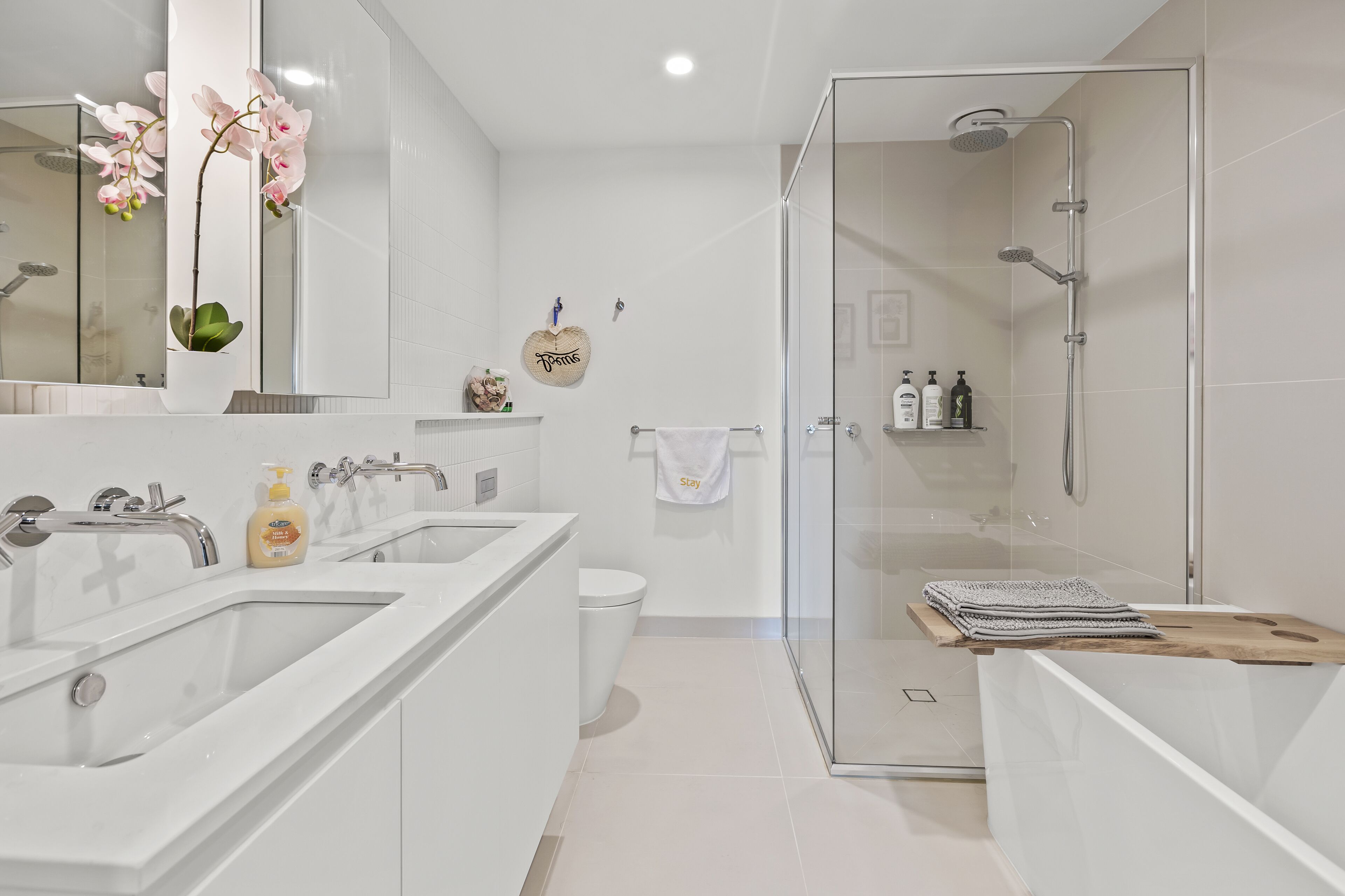 Un baño moderno con dos lavamanos, cabina de ducha con paredes de vidrio y un perchero para toallas.