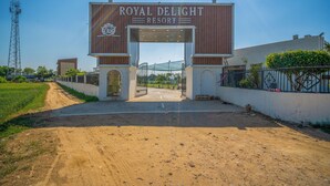 La entrada al Royal Delight Resort, con cielo despejado y un camino de tierra que lleva a la puerta.