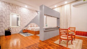 Un dormitorio moderno con cama, televisor y zona de comedor con sillas.