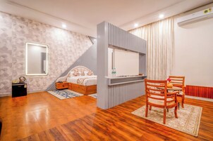 A modern bedroom with a bed, a TV, and a dining area with chairs.