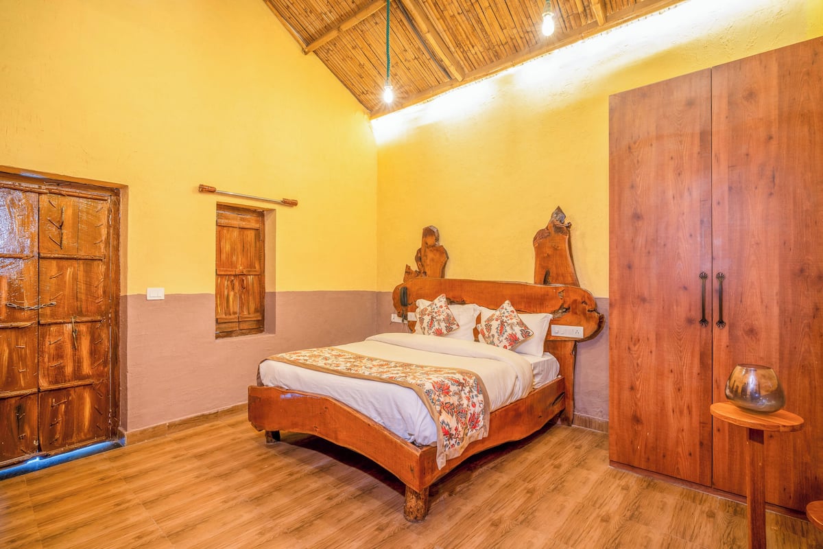 A wooden bed with a headboard, a wardrobe, and a small table with a bowl.