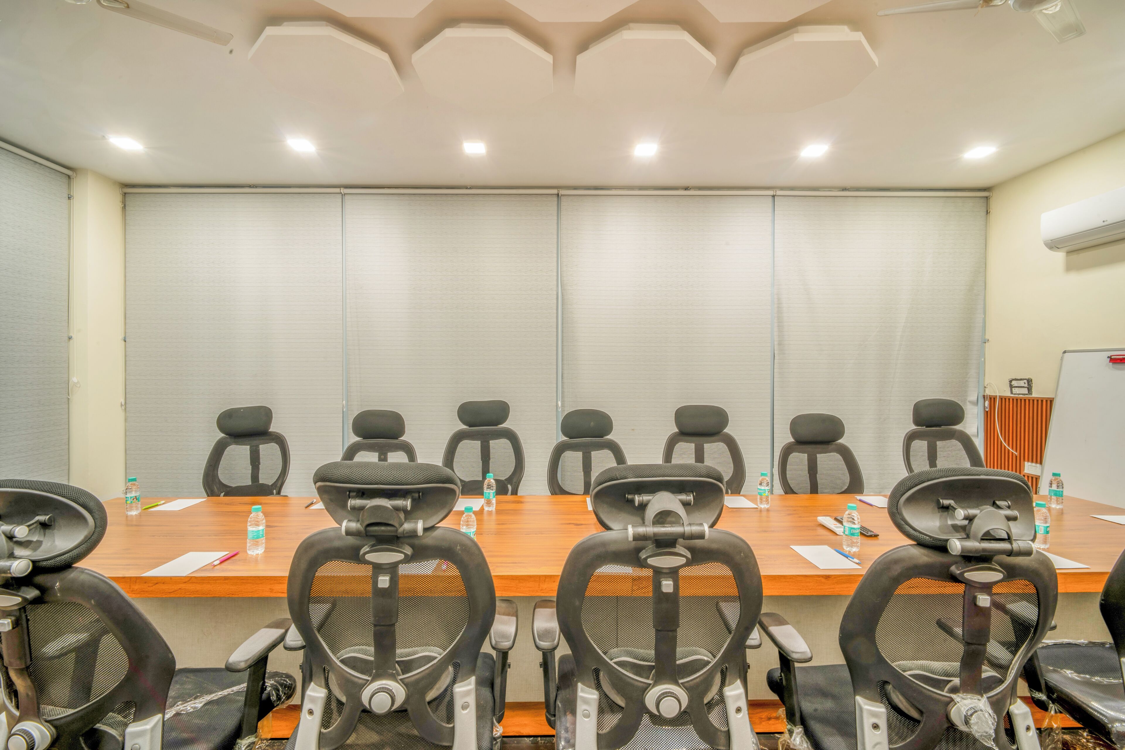 A conference room with a long table, multiple chairs, and a whiteboard.