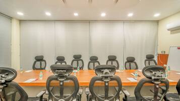 A conference room with a long table, multiple chairs, and a whiteboard.