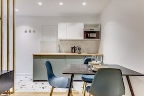 A modern kitchen with a central island, blue chairs, and a dining table set for two. - The Starry Night - Modern by Mon Petit Faré (Paris)