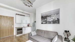A modern living room with a grey sofa, a white coffee table, and a cityscape painting on the wall. - The Vendôme - Elegant&Business by Mon Petit Faré (Paris)