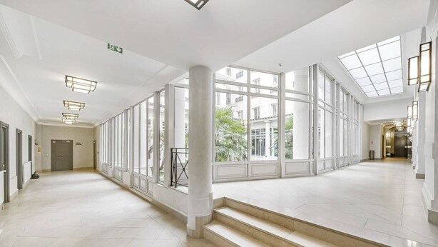 A spacious, well-lit hallway with large windows, a staircase, and a door at the end. - The Vendôme - Elegant&Business by Mon Petit Faré (Paris)