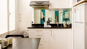 A compact kitchen with white cabinets, a black countertop, a microwave, and a refrigerator. - Hidden beauty - low cost -courtyard -Best location (Paris)