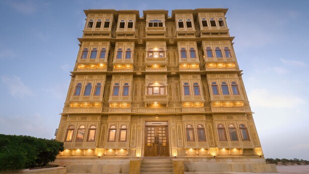 Un edificio de varios pisos con detalles arquitectónicos ornamentados, ventanas amplias y una entrada central.