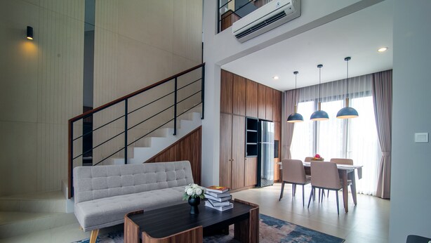 A modern living room with a sofa, coffee table, and dining area with chairs and a table. - De Kunyit Villa (Tabanan)