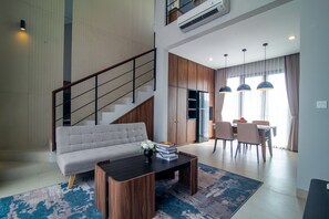 A modern living room with a sofa, coffee table, and dining area with chairs and a table. - De Kunyit Villa (Tabanan)
