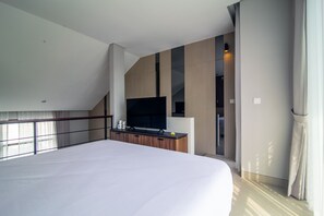 A modern hotel room with a large bed, a flat-screen TV, and a view of the outside. - De Kunyit Villa (Tabanan)