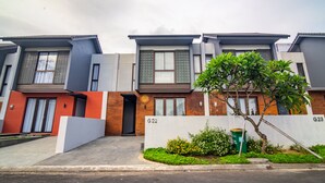 A row of modern residential buildings with numbered units G22 and G23, featuring balconies, large windows, and a small garden area. - De Kunyit Villa (Tabanan)