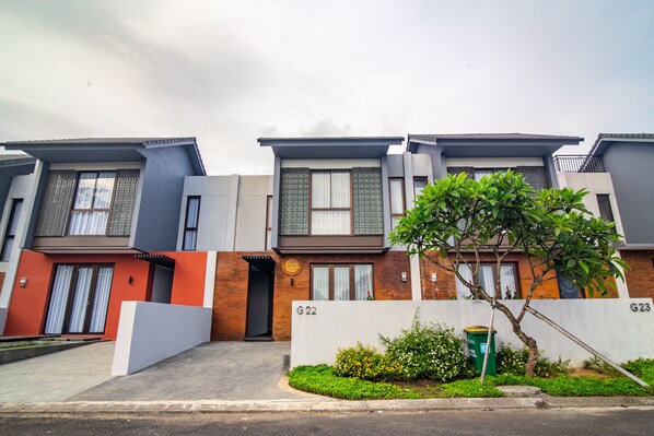 A row of modern residential buildings with numbered units G22 and G23, featuring balconies, large windows, and a small garden area. - De Kunyit Villa (Tabanan)