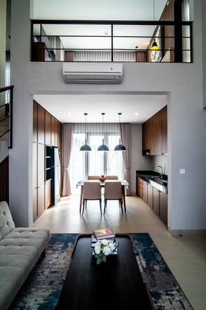 A modern apartment with a dining area, kitchen, and a sofa. - De Kunyit Villa (Tabanan)