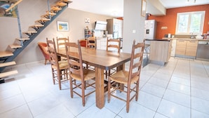 Een moderne keuken met een eethoek, voorzien van een houten tafel en stoelen, een trap en een keukeneiland.
