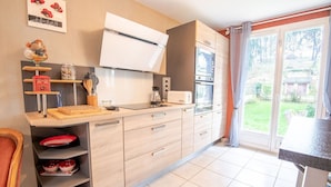 Een moderne keuken met een inbouwoven, magnetron en een groot raam met gordijnen.