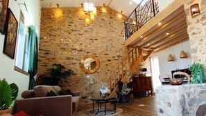 Un vaste espace de vie agrémenté d’un mur en pierre, d’un escalier en bois et d’un mobilier moderne.