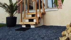 Un edificio con fachada de ladrillo, ventanas amplias y una escalera de madera que lleva a una puerta.