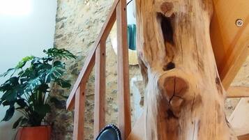 Une sculpture en bois dans une pièce dont le mur est en pierre et qui contient un escalier.