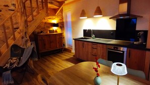 Una cocina acogedora con armarios de madera, una mesa de comedor de madera y lámparas colgantes.
