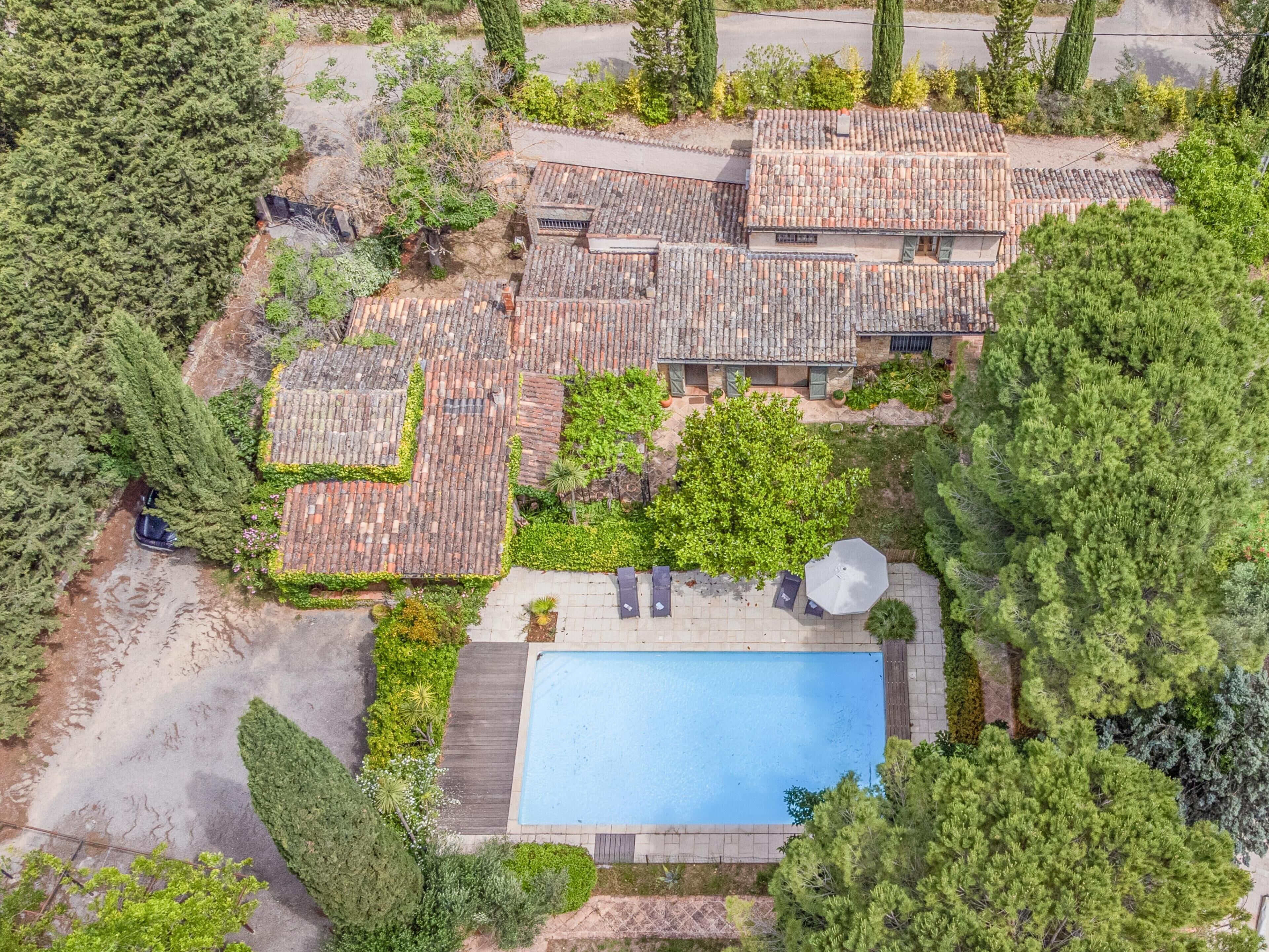 An aerial view of a residential area with multiple houses, a swimming pool, and surrounding greenery.