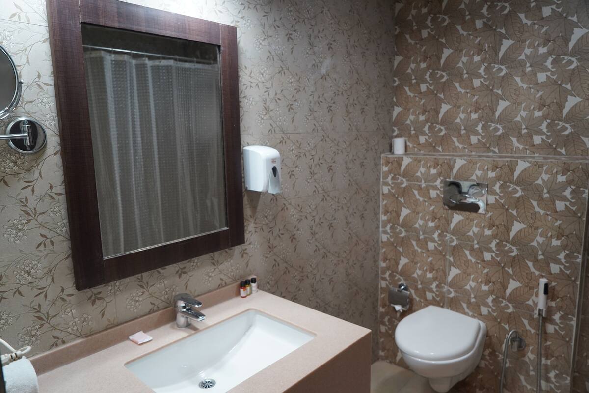 A bathroom with a sink, mirror, toilet, and shower.