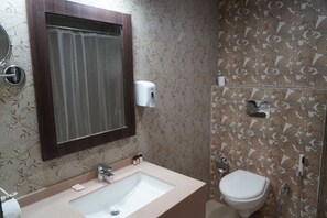 A bathroom with a sink, mirror, toilet, and shower. - Hotel Forest Avenue (Dehradun)