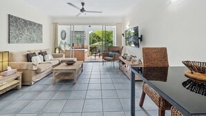 A spacious living room with a sofa, coffee table, and wicker furniture.