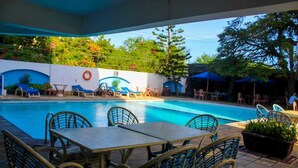 A poolside area with lounge chairs, a table, and a lifebuoy on the wall.