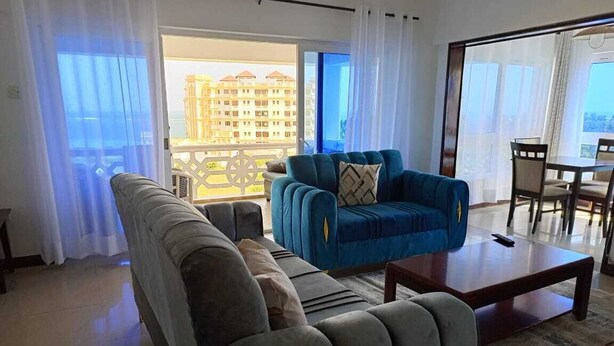A living room with a sofa, a blue armchair, and a coffee table.