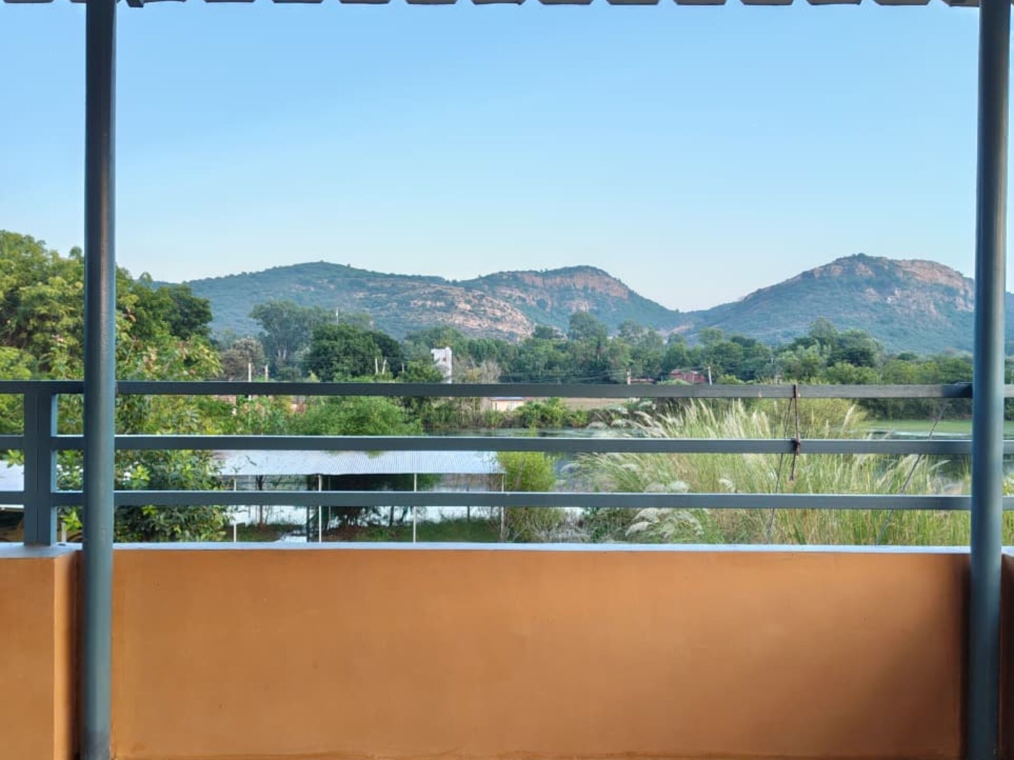 A balcony with a view of mountains and greenery.